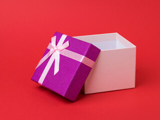 Gift box with open lid on red background.