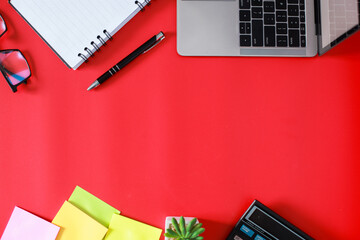 Flat lay top view of stylish home office workspace with laptop, book, succulent and accessories isolated on red background, free space or copy space