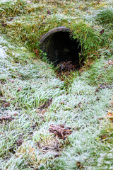 Frosty flood control, grass covered rainwater drainage ditch with metal culvert pipe
