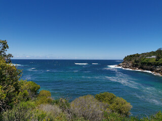 Stunning view of a deep blue sea and small beach from a coastal trail lookout, Sydney, New South Wales, Australia
