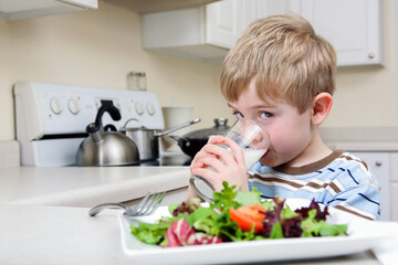 Obraz na płótnie Canvas Young boy drinking milk and eating a salad