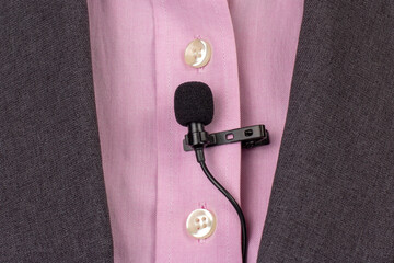 The lavalier microphone is secured with a clip on a women's shirt close-up. Audio recording of the...