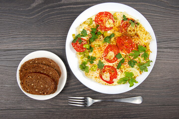 cooked fried omelet with herbs and vegetables in a white plate on a wooden table