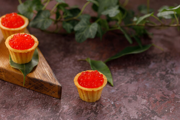 Appetizing tartlets with red caviar on a decorative board for serving. Holiday concept. Close-up. Copy space.