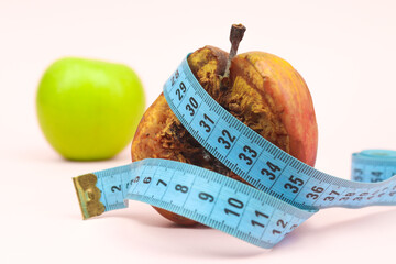 tape measure wrapped in rotten apple. Healthy apples standing behind. diet and weight loss concept