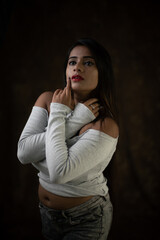 Studio portrait of a beautiful and young Indian Bengali female model in white cold shoulder top and...