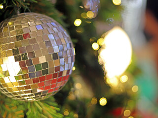 Christmas Tree fir close up decoration with big silver mirror and golden glitter ball has blur bokeh light background selective focus, has copy space for Christmas season, invitation card background.