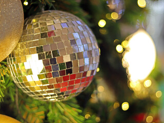 Obraz premium Christmas Tree fir close up decoration with big silver mirror and golden glitter ball has blur bokeh light background selective focus, has copy space for Christmas season, invitation card background.