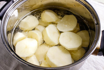 Raw peeled potatoes in a pot of water before cooking.