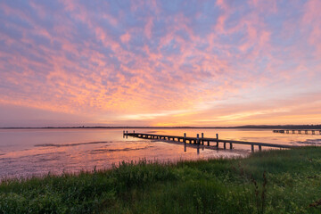 Colorful sunrise cloud over a jetty on the lake side.