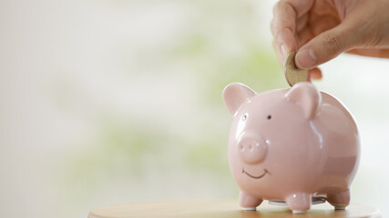 豚の貯金箱に小銭を入れる女性の手