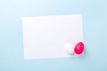 Spring mockup with Easter eggs and blank of white paper on blue background. Easter concept. Copy space