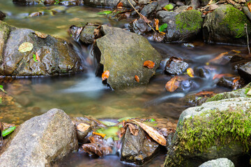 Close-up of the waterfall movement. The stream of water flows around the rock and falls down. Long exposure shot.
