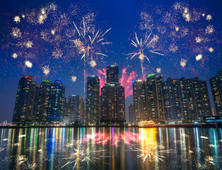 Busan Marina city skyscrapers illluminated sky with fireworks at night with reflection in water, South Korea