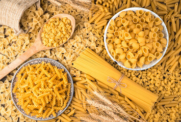 Wheat and lots of different kinds of pasta on the table. The view from the top. Culinary background. The concept of food.