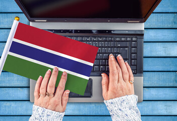 woman hands and flag of Gambia on computer, laptop keyboard