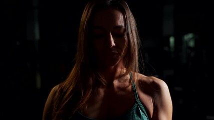 Sportive girl in the gym reels a wrist strap on her arm. - Powered by Adobe