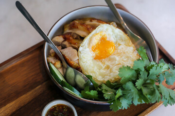 Chicken  rice with coriander and .fried egg in bowl.