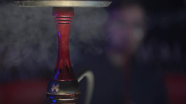 Close-up image of a part of a hookah with swirling smoke from it.
