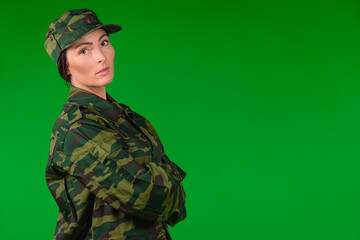 Serious woman in military uniform looks at the camera. Green background and empty side ad space.