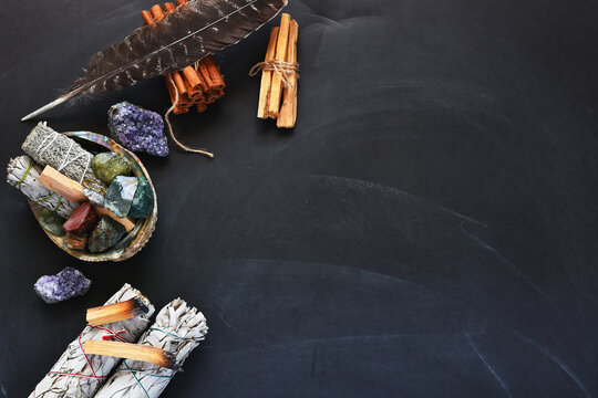 A top view image of several items of a sacred smudge kit on a black background.  