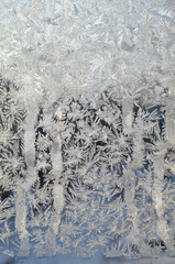 Frost patterns on the frozen window. Hoarfrost background, frost texture, Christmas pattern on winter window glass. Backdrop for Christmas and New Year.