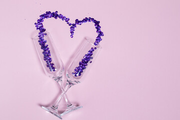 Champagne glass with purple sequins scattered in the form of heart. Valentine's Day design and free space