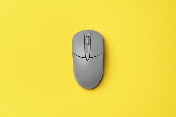 Gray computer mouse on yellow background top view