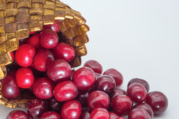 Cherry berries pour out of the birch bark box. White background.