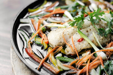 chinese style steamed fish fillet with vegetables on hot plate