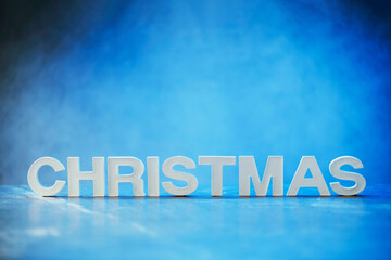 Word Christmas made of white concrete letters on blue light background. Copy space for your creative design. Festive invitation, greeting card