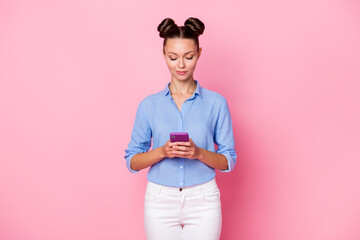 Back view photo portrait of girl typing message using smartphone smiling browsing internet isolated on pastel pink color background