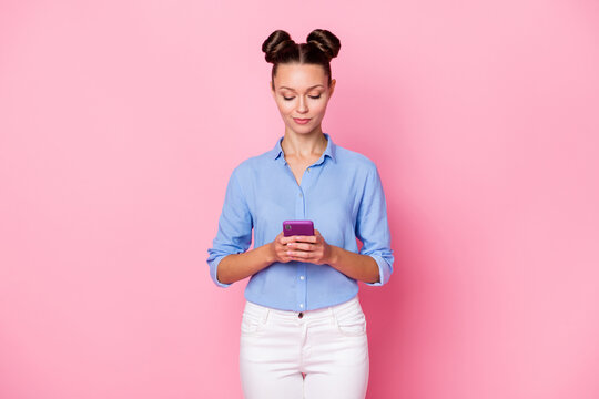 Back view photo portrait of girl typing message using smartphone smiling browsing internet isolated on pastel pink color background