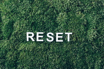 Word Reset on moss, green grass background. Top view. Copy space. Banner. Biophilia concept. Nature...