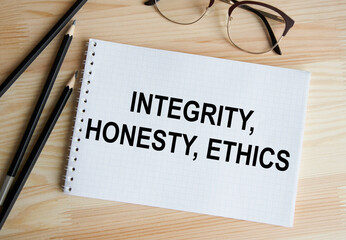 In the notebook, the text of INTEGRITY, HONESTY, ETHICS, next to pencils and glasses.