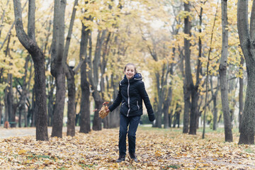 a girl running through the park and enjoys autumn, beautiful nature with yellow leaves