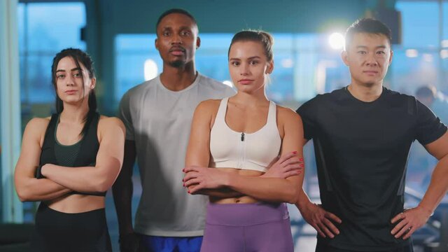 Portrait sportive young team of multi-ethnic attractive athletes standing together smiling enjoying bodycare bodybuilding workout in the gym.