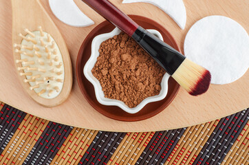 Cocoa powder in a bowl for preparing face and hair mask. Homemade beauty treatment and spa recipe. Top view, copy space.