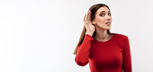 Young pretty brunette woman holding hand near ear trying to listen something. Copy space