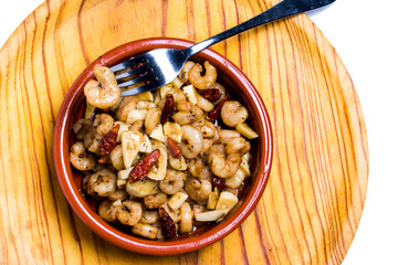 Prawns with garlic and cayenne in a ceramic bowl on a wooden tray