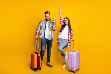Photo portrait full body view of cheerful excited couple with suitcases isolated on vivid yellow colored background