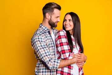 Photo portrait of man hugging woman from behind looking at each other isolated on vivid yellow colored background