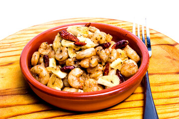 Prawns with garlic and cayenne in a ceramic bowl on a wooden tray