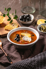 Traditional russian meat hodgepodge soup solyanka on rustic background