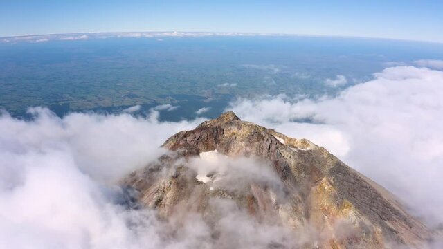 Volcano peak - dramatic drone aerial footage with cloud moving on the snowy peak of Mount Taranaki, Egmont National Park, New Zealand in 4k