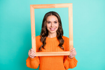 Photo of young attractive girl hold wooden photo frame look through it isolated over teal color...