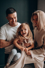 Photoshoot of a happy young family. Dad, mom and daughter. Studio photography.