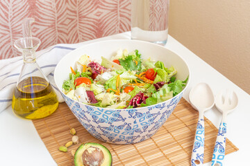 Salad with olive oil, avocado and glass water bottle in the background