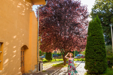 Girl in dress and hat stands in park near Ecaterina Gate. Catherine's Gate was built for the access from Schei district into the fortress of Brasov in Transylsvania. Going for a tour walk in Romania