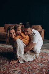 Photoshoot of a happy young family. Dad, mom and daughter. Studio photography.